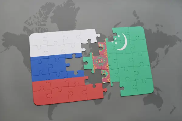 Puzzle avec le drapeau national de la Russie et le turkmène sur un fond de carte du monde . — Photo