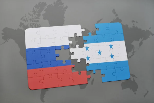 Puzzel met de nationale vlag van Rusland en Honduras op een wereld kaart achtergrond. — Stockfoto