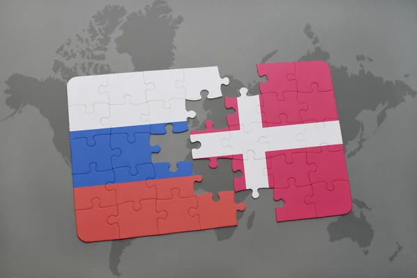 Puzzle con la bandiera nazionale di Russia e denmark su uno sfondo mappa del mondo . — Foto Stock