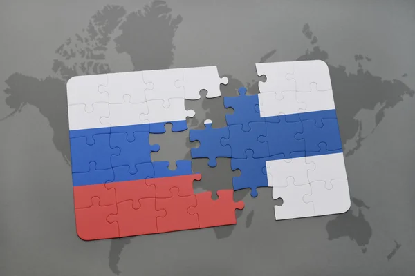 Puzzle con la bandiera nazionale di Russia e Finlandia su uno sfondo mappa del mondo . — Foto Stock