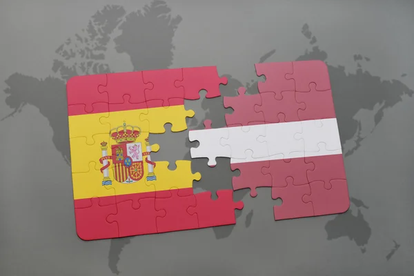 Puzzle s národní vlajkou Španělska a Lotyšska na pozadí světové mapy. — Stock fotografie