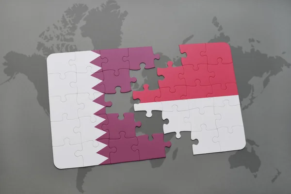 Puzzel met de nationale vlag van Qatar en Indonesië op een wereld kaart achtergrond. — Stockfoto