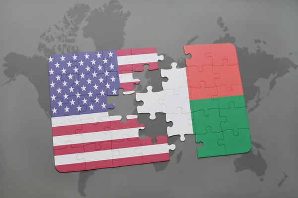 Puzzle mit der Nationalflagge der Vereinigten Staaten von Amerika und Madagaskar auf einer Weltkarte Hintergrund. — Stockfoto