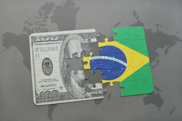 Rompecabezas con la bandera nacional de Brasil y el billete de dólar en un mapa del mundo fondo . — Foto de Stock