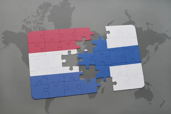 Puzzle avec le drapeau national des Pays-Bas et de la Finlande sur un fond de carte du monde . — Photo