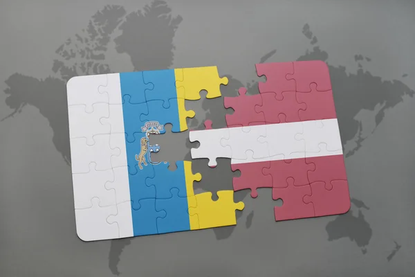 Quebra-cabeça com a bandeira nacional de ilhas canárias e latvia em um fundo de mapa do mundo . — Fotografia de Stock