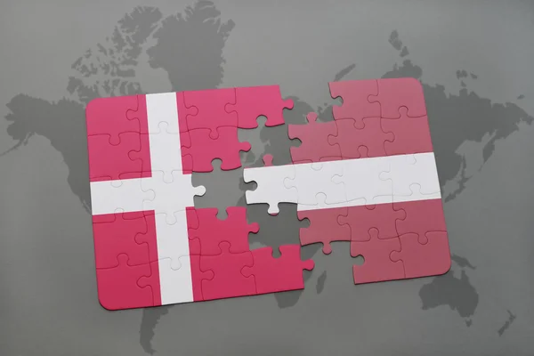 Bir dünya haritası arka plan üzerinde Danimarka ve Letonya ulusal bayrağı ile bulmaca. — Stok fotoğraf