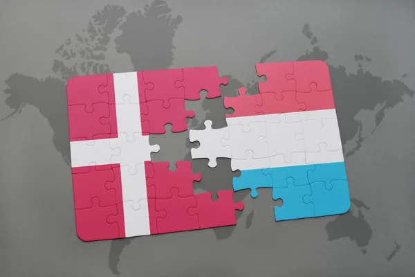 Hádanka s národní vlajkou Dánska a Lucemburska na pozadí mapy světa. — Stock fotografie