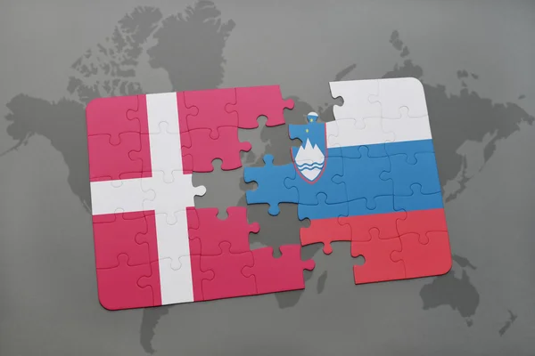 Quebra-cabeça com a bandeira nacional de denmark e slovenia em um fundo de mapa do mundo . — Fotografia de Stock
