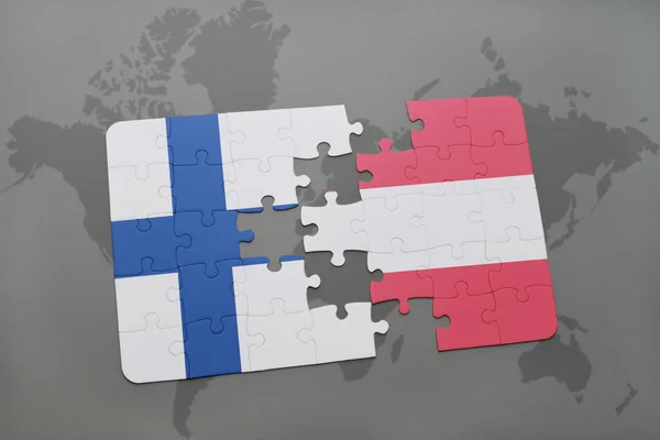 Puzzle avec le drapeau national de la Finlande et l'Autriche sur un fond de carte du monde . — Photo