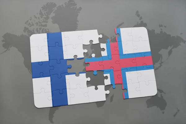 Rompecabezas con la bandera nacional de las islas Feroe y Finlandia en un mapa del mundo de fondo . — Foto de Stock