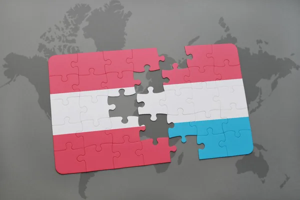 Puzzle con la bandiera nazionale di austria e luxembourg su sfondo mappa del mondo . — Foto Stock