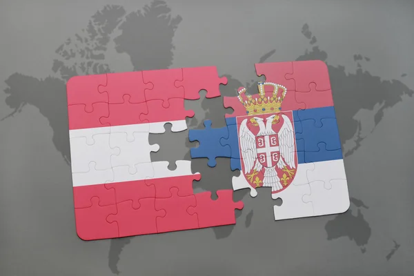 Puzzel met de nationale vlag van Oostenrijk en Servië op een wereld kaart achtergrond. — Stockfoto