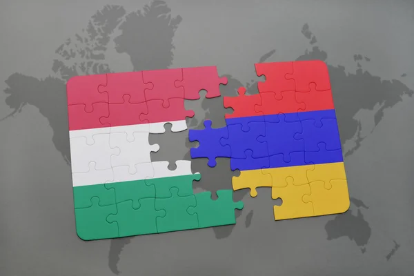 Puzzle avec le drapeau national de la Hongrie et l'arménie sur un fond de carte du monde . — Photo