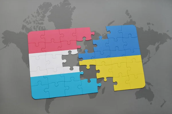 Quebra-cabeça com a bandeira nacional de luxembourg e ucraniana em um fundo de mapa do mundo . — Fotografia de Stock