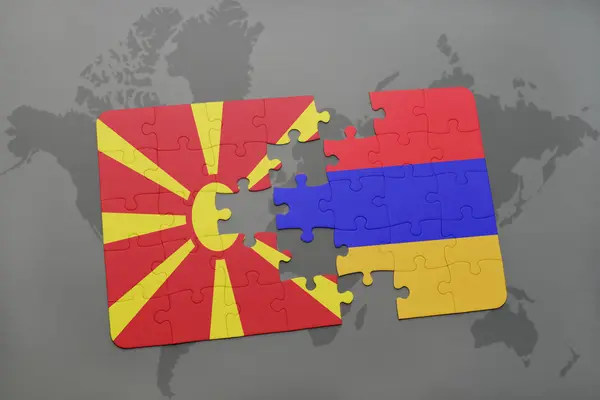 Puzzel met de nationale vlag van Macedonië en Armenië op een wereld kaart achtergrond. — Stockfoto