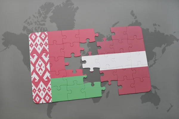 Puzzel met de nationale vlag van Wit-Rusland en Letland op een wereld kaart achtergrond. — Stockfoto
