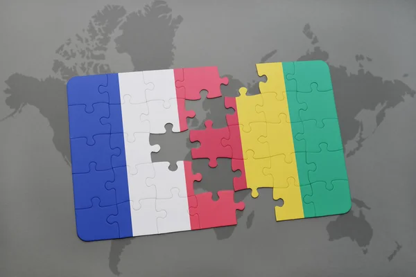 Puzzle avec le drapeau national de la France et de la Guinée sur fond de carte du monde . — Photo