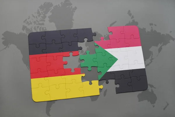 Rompecabezas con la bandera nacional de Alemania y Sudán en un mapa del mundo de fondo . — Foto de Stock