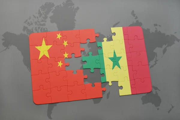 Rompecabezas con la bandera nacional de China y Senegal en un fondo de mapa del mundo . —  Fotos de Stock