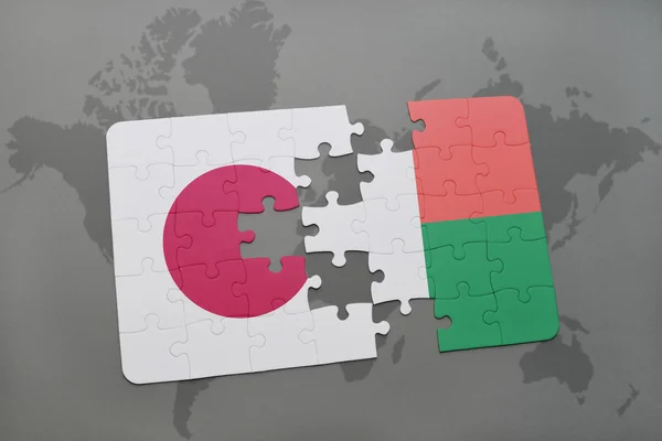Puzzel met de nationale vlag van Japan en Madagaskar op een wereld kaart achtergrond. — Stockfoto