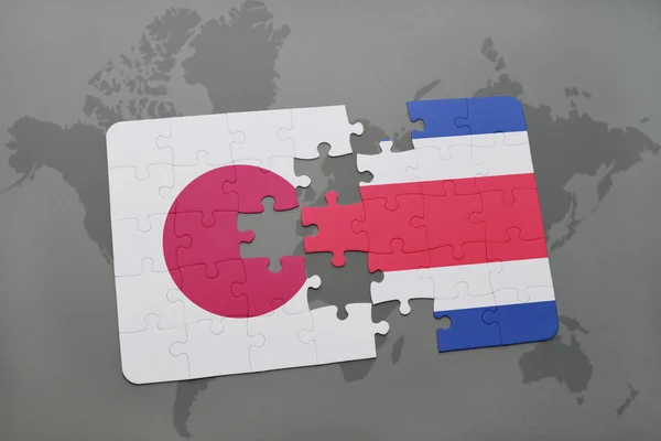 Puzzle avec le drapeau national du Japon et de la Costa Rica sur fond de carte du monde . — Photo