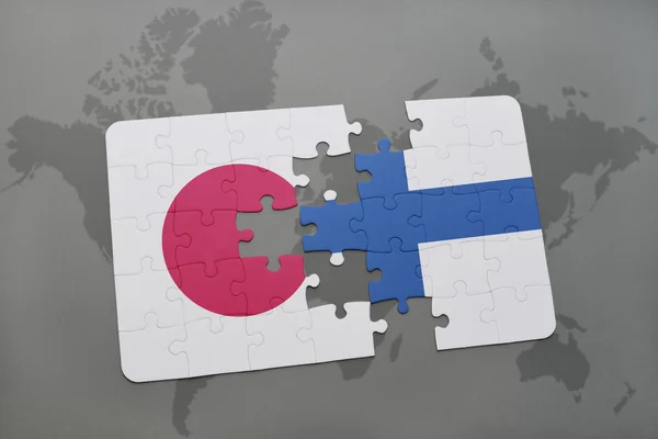 Puzzel met de nationale vlag van Japan en Finland op een wereld kaart achtergrond. — Stockfoto