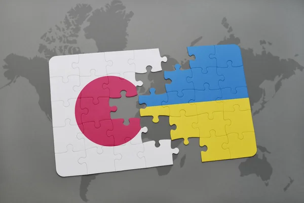 Puzzle avec le drapeau national du Japon et de l'ukraine sur fond de carte du monde . — Photo