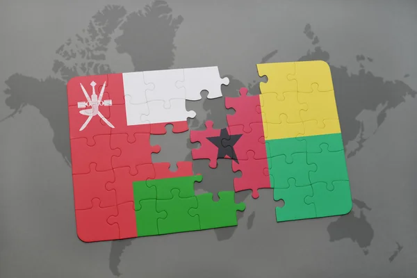 Puzzel met de nationale vlag van Oman en Guinee-Bissau op een wereld kaart achtergrond. — Stockfoto