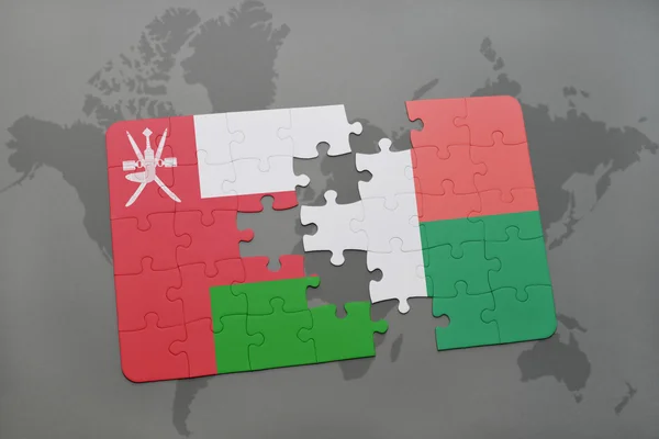 Puzzel met de nationale vlag van Oman en Madagaskar op een wereld kaart achtergrond. — Stockfoto