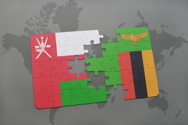 Puzzel met de nationale vlag van Oman en Zambia op een wereld kaart achtergrond. — Stockfoto