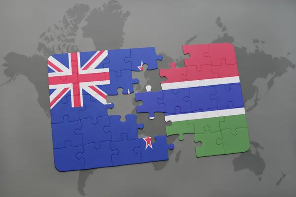Quebra-cabeça com a bandeira nacional da Nova Zelândia e gâmbia em um fundo de mapa do mundo . — Fotografia de Stock
