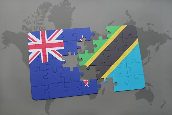 Rompecabezas con la bandera nacional de Nueva Zelanda y Tanzania en un mapa del mundo de fondo . — Foto de Stock