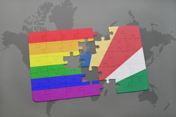 Puzzle with the national flag of seychelles and gay rainbow flag on a world map background. — Stock Photo, Image