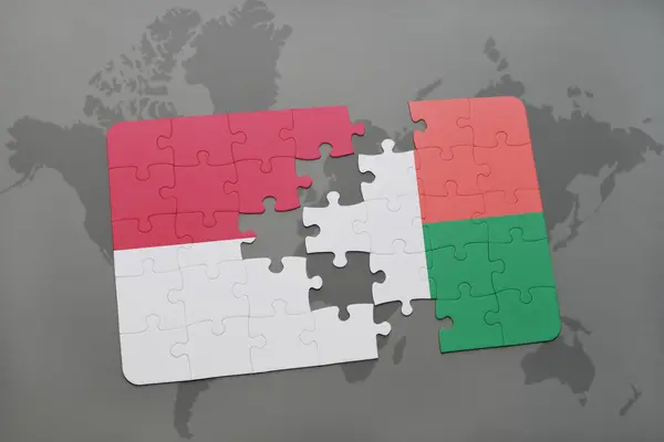Puzzel met de nationale vlag van Indonesië en Madagaskar op een wereld kaart achtergrond. — Stockfoto