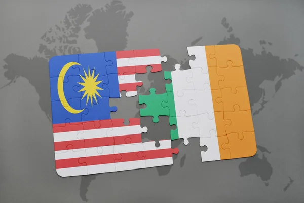Puzzle con la bandiera nazionale di Malesia e Irlanda su uno sfondo mappa del mondo . — Foto Stock