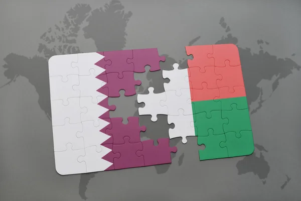 Puzzel met de nationale vlag van Qatar en Madagaskar op een wereld kaart achtergrond. — Stockfoto