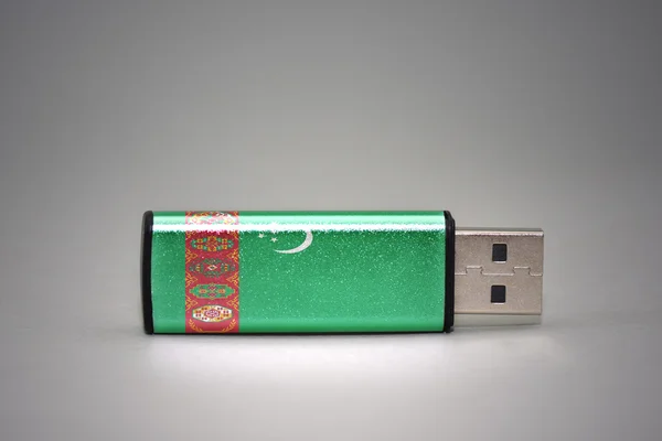 usb flash drive with the national flag of turkmenistan on gray background.