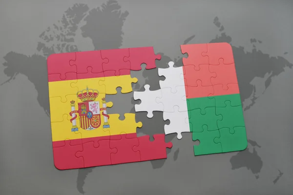 Puzzle with the national flag of spain and madagascar on a world map background. — Stock Photo, Image