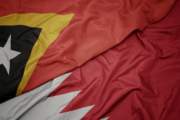 waving colorful flag of bahrain and national flag of east timor. macro