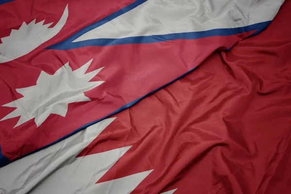 waving colorful flag of bahrain and national flag of nepal. macro