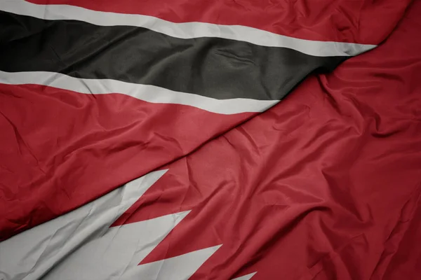 waving colorful flag of bahrain and national flag of trinidad and tobago. macro