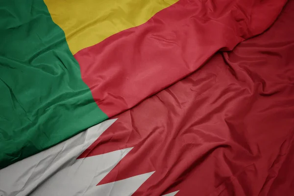 waving colorful flag of bahrain and national flag of benin. macro