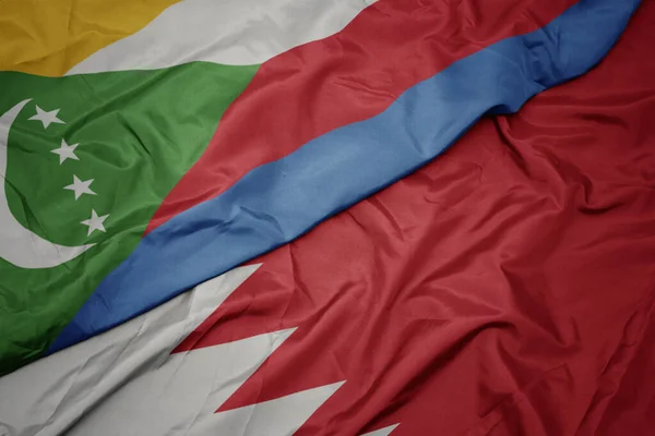 waving colorful flag of bahrain and national flag of comoros. macro