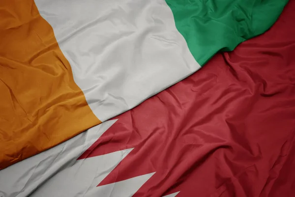 waving colorful flag of bahrain and national flag of cote divoire. macro