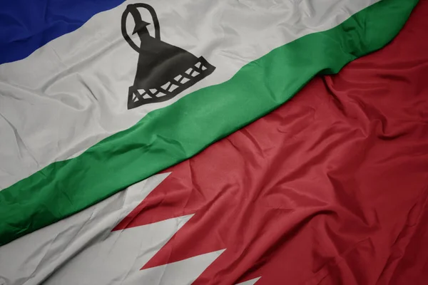 waving colorful flag of bahrain and national flag of lesotho. macro