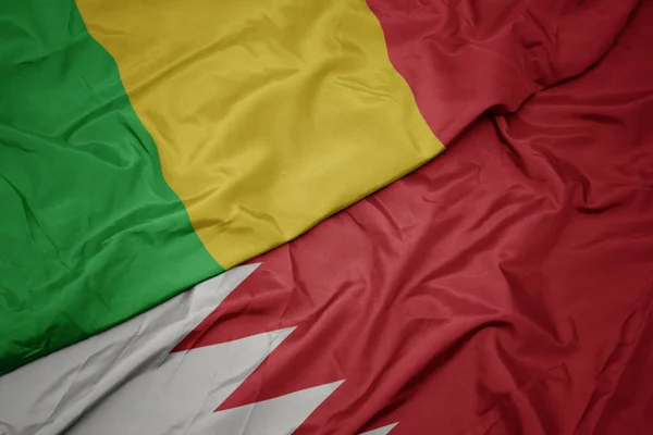 waving colorful flag of bahrain and national flag of mali. macro