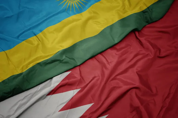 waving colorful flag of bahrain and national flag of rwanda. macro