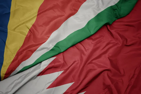 waving colorful flag of bahrain and national flag of seychelles. macro