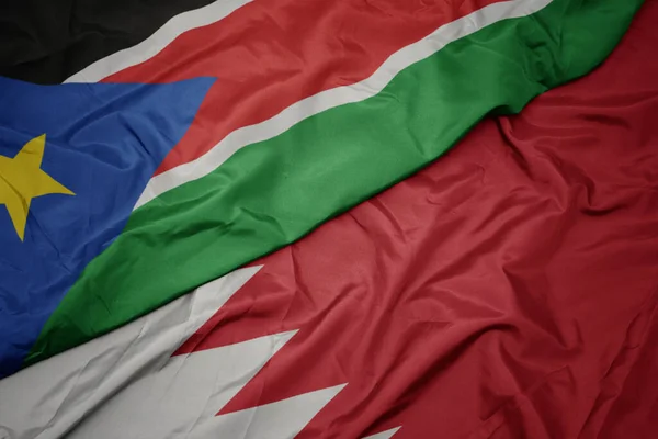 waving colorful flag of bahrain and national flag of south sudan. macro